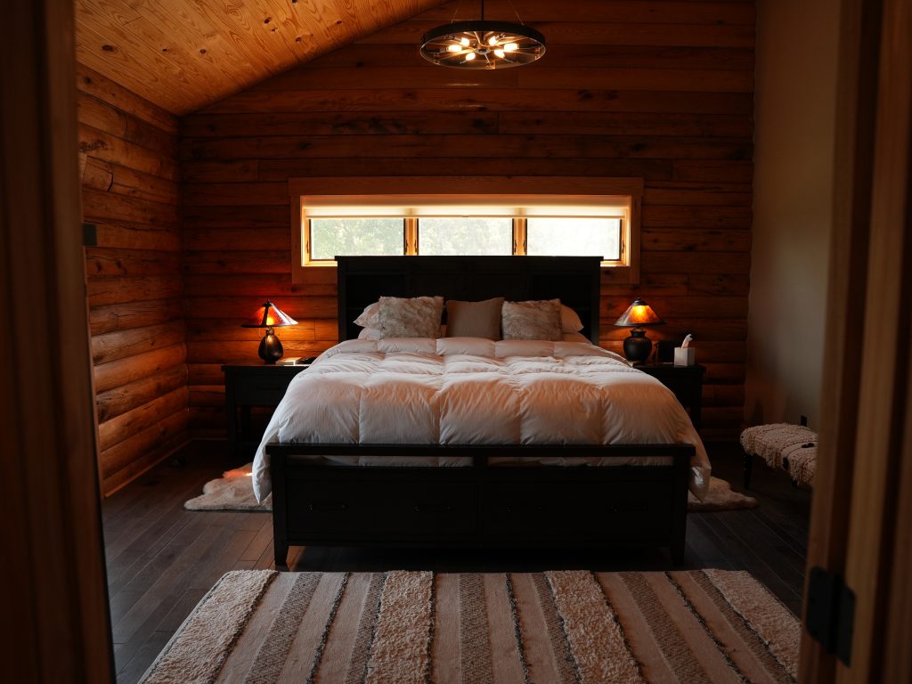 A picture of a bed and lamps in a bedroom of a log home