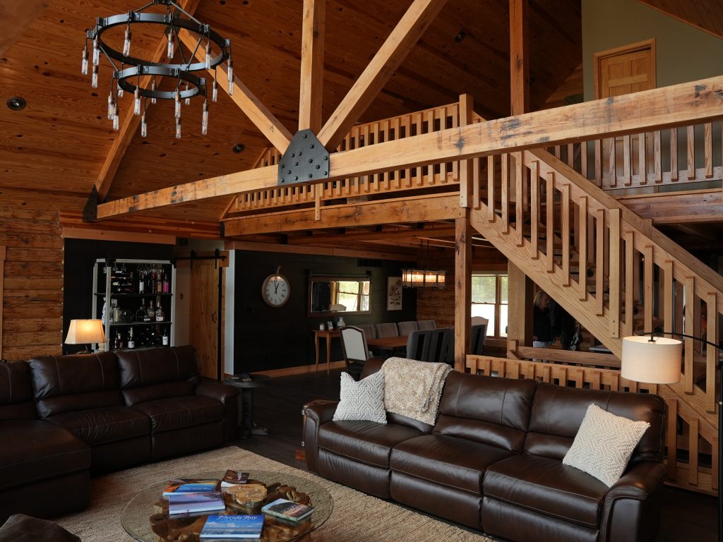 A picture of a couches in the living living room and a staircase to the loft in a log home