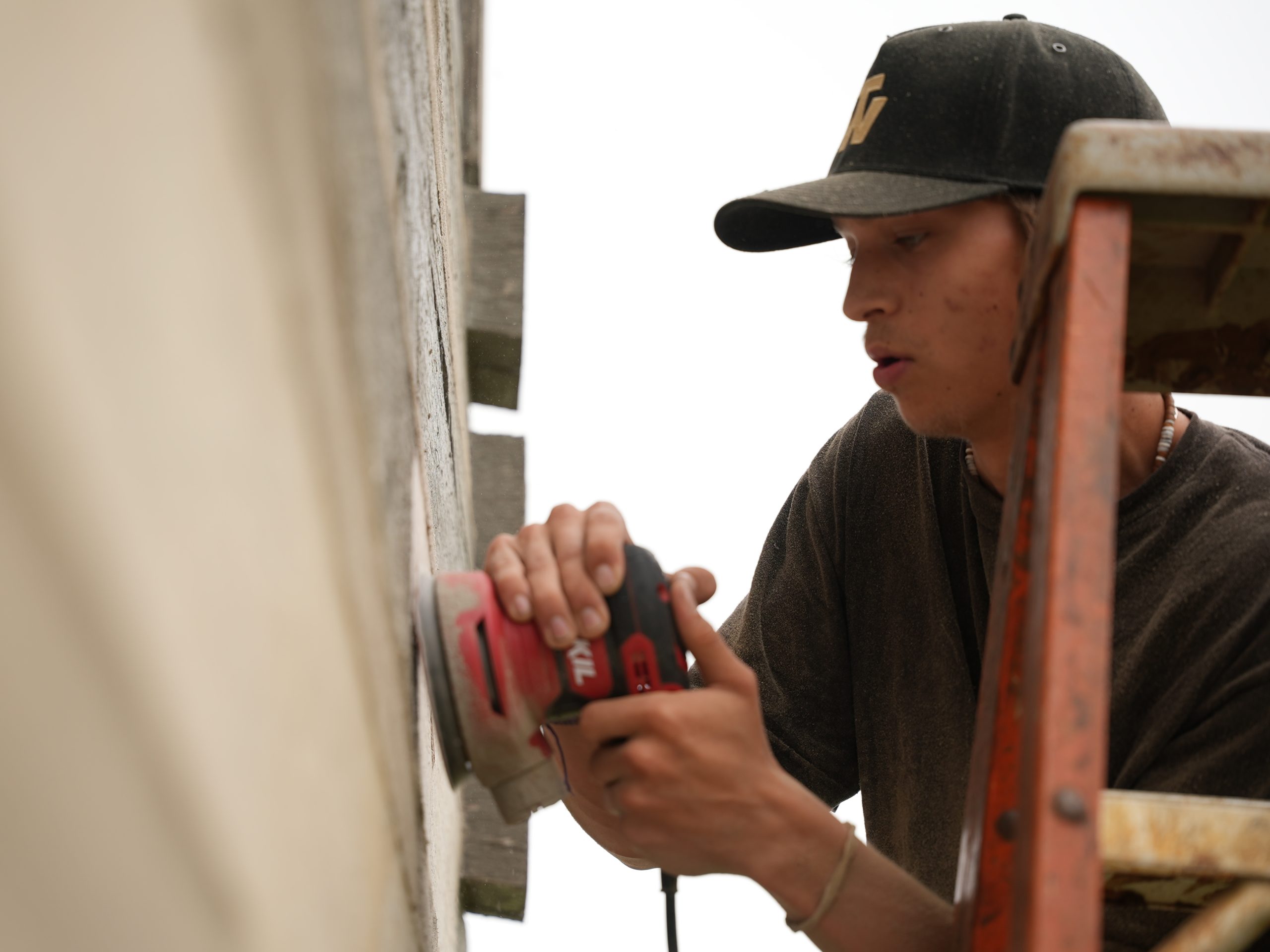 Maintenance crew sanding the exterior of a log home