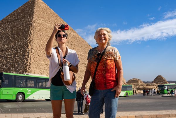 Two women standing in front of a pyramid in Egypt taking a picture