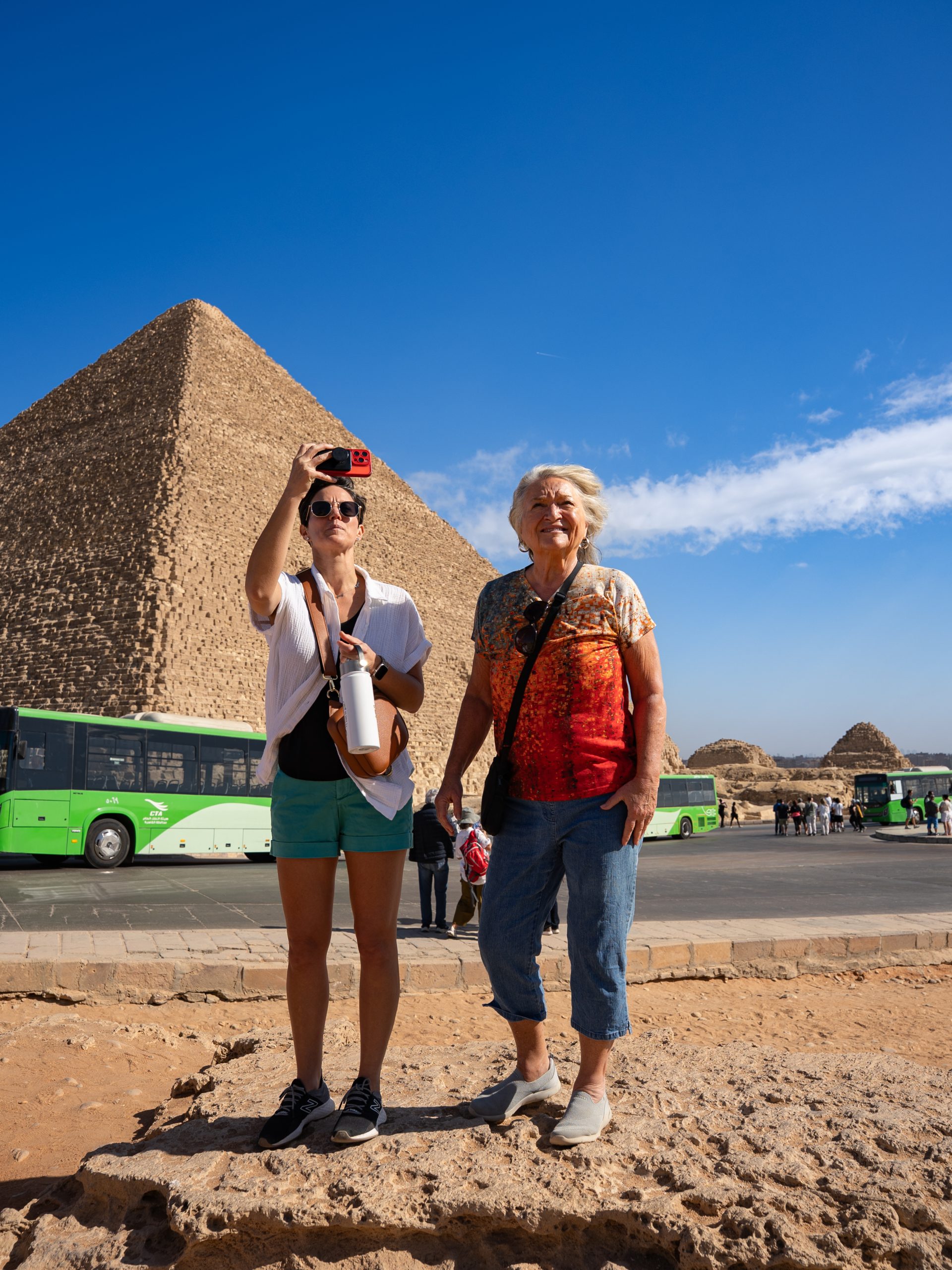Two women standing in front of a pyramid in Egypt taking a picture