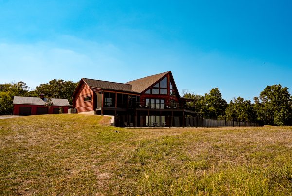 Log home in a field with trees in the background