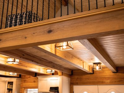 Log home ceiling and beams with lights hanging underneath the loft